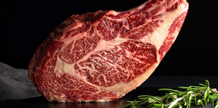 Close-up of marbled tomahawk wagyu steak on a wooden board.