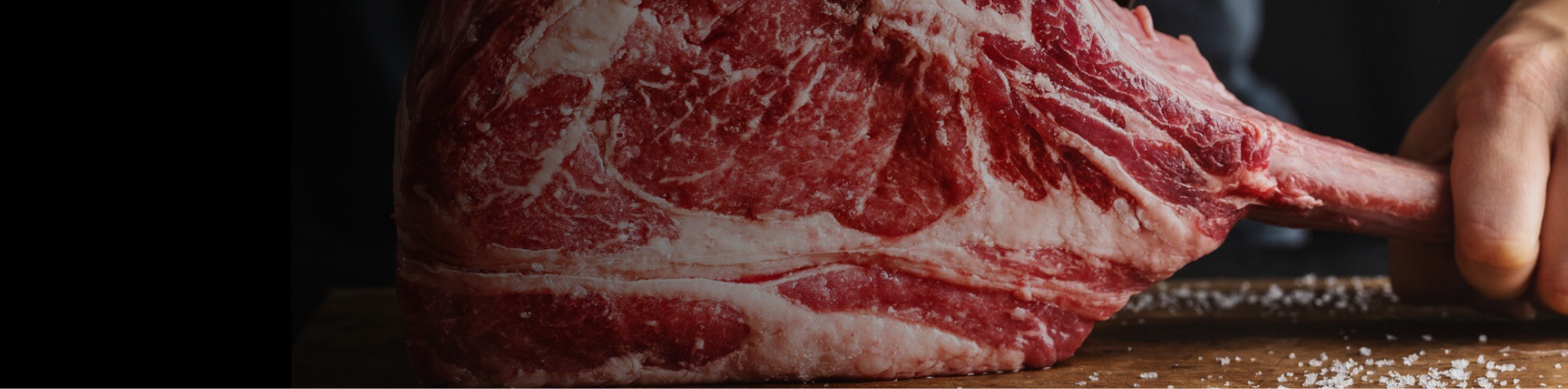 Hand holding a perfectly uncooked Wagyu beef steak.