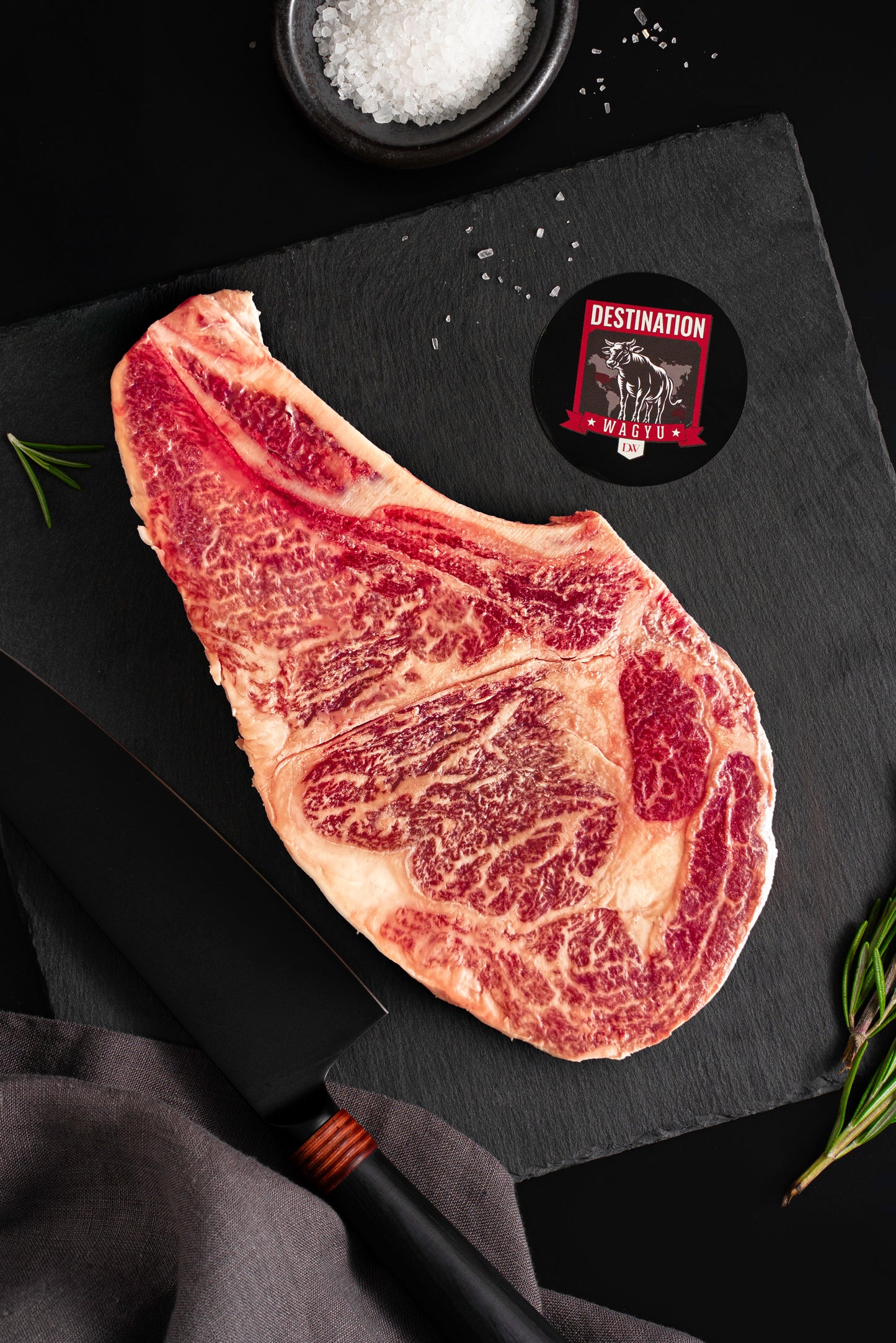 An Australian wagyu bone in ribeye steak on a black slate board