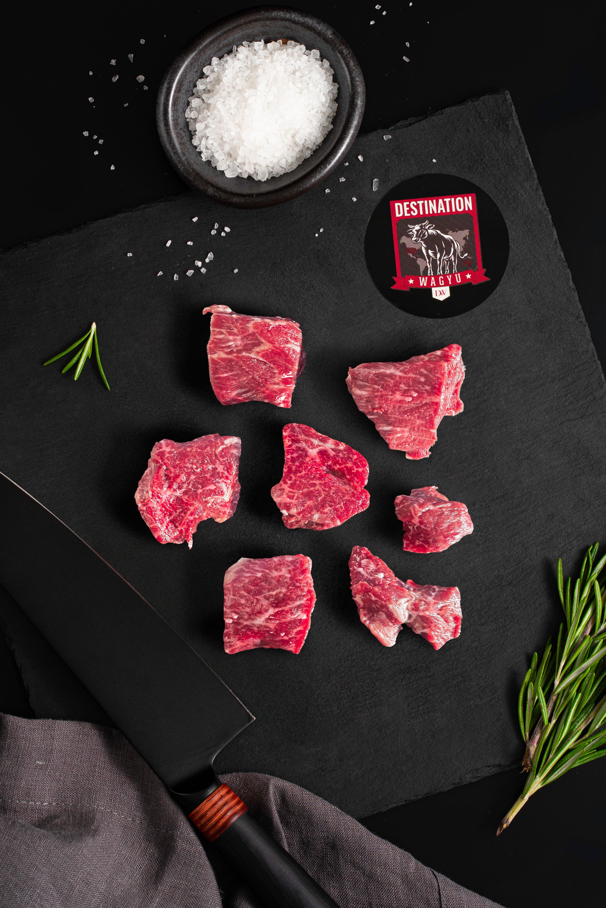 Australian wagyu filet cubes sitting on a black slate board with knife and salt
