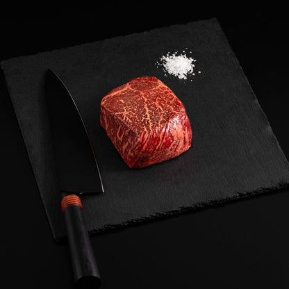 An Australian Wagyu Full Blood Top Sirloin Steak with salt and chef's knife on a black slate, isolated on black background.