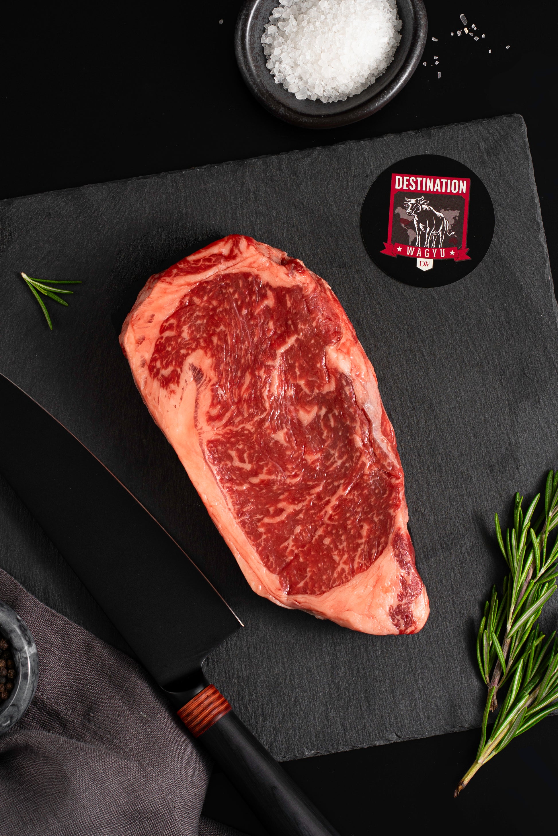 An Australian wagyu striploin steak sits on a black slate board