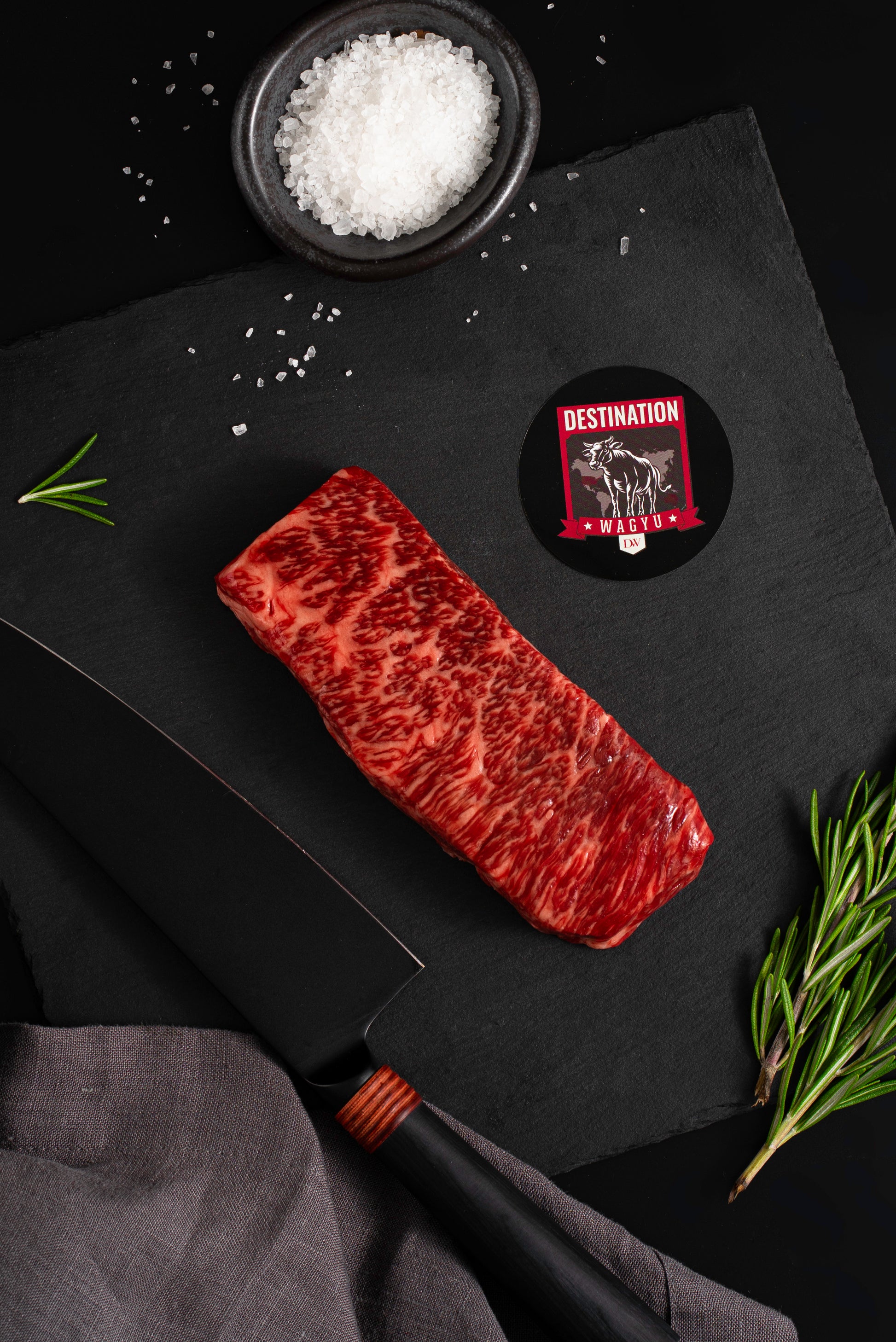 A full blood australian wagyu denver steak on a black board with salt and knife