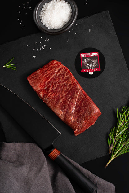 An Australian wagyu full blood flat iron steak on a black slate board with knife and salt 