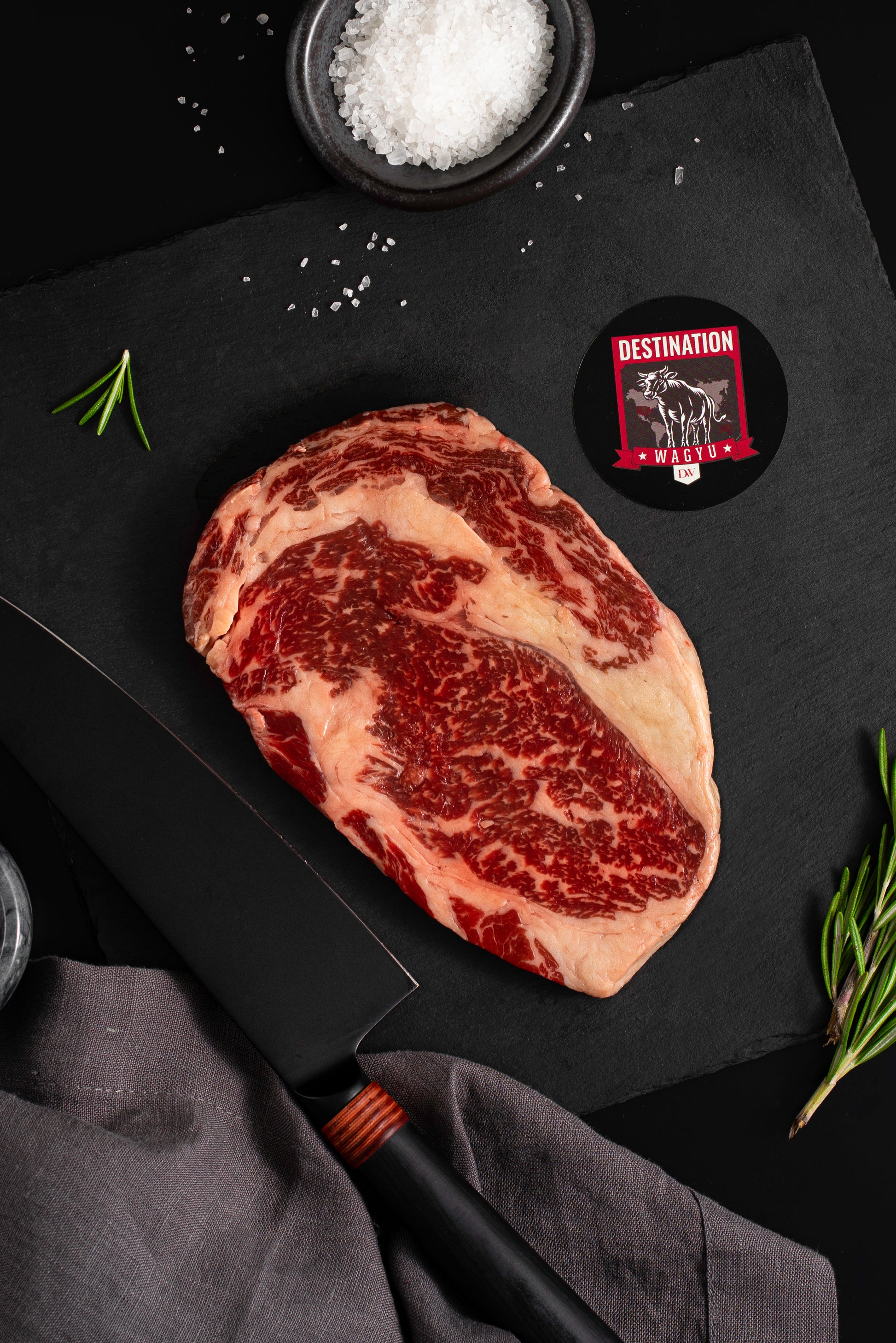 an australian wagyu ribeye steak in 10oz size on a black board with salt and knife 