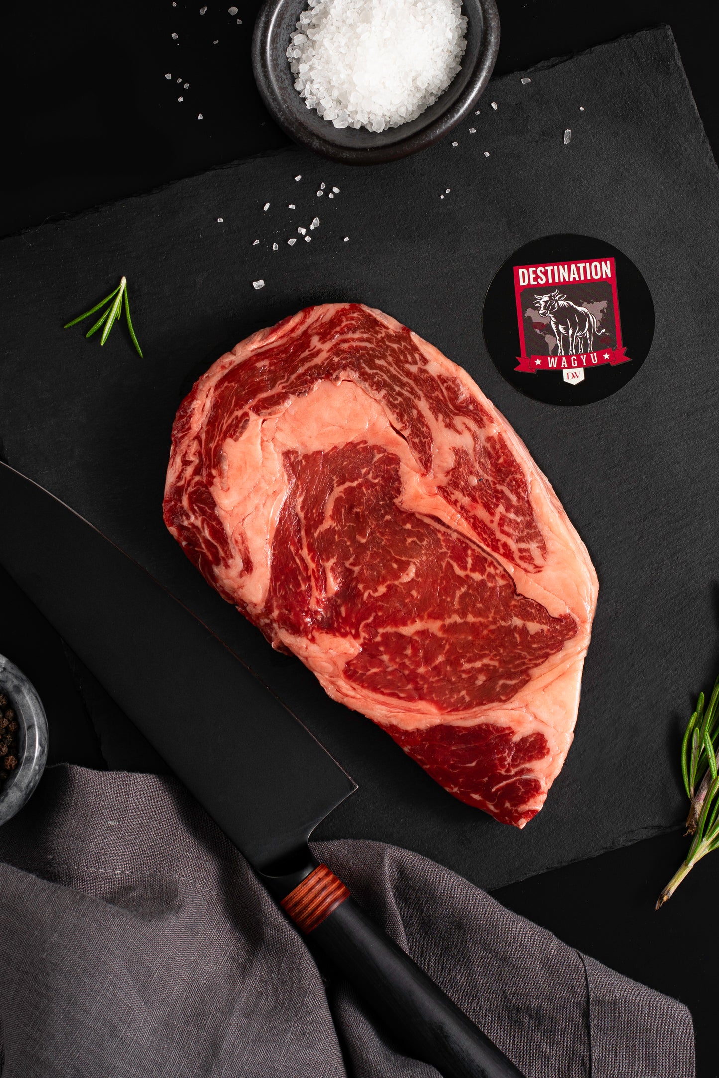 American Wagyu Ribeye steak in a 16oz size on a black board with knife and salt