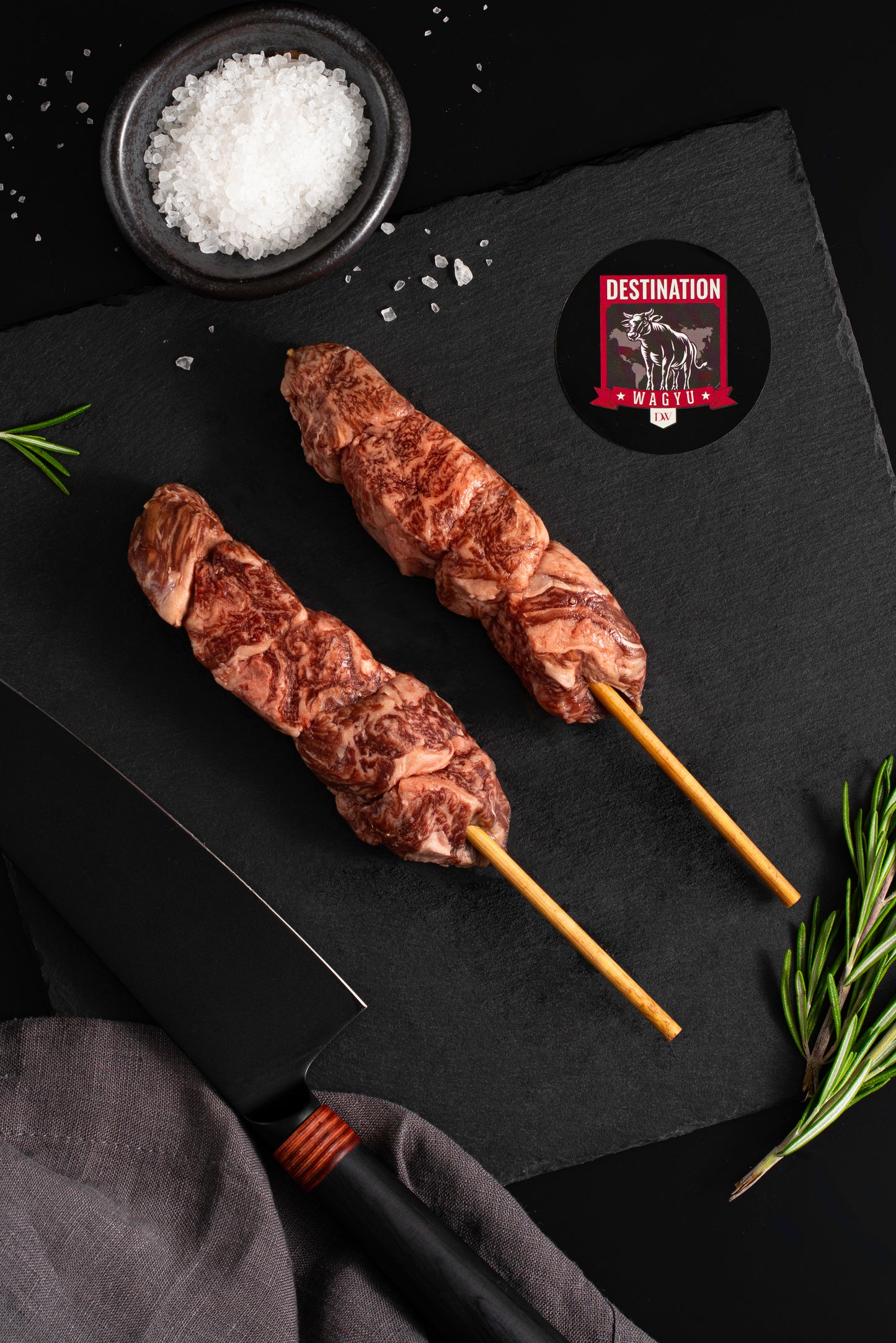 two Japanese A5 wagyu filet mignon skewers on a black board with salt and knife