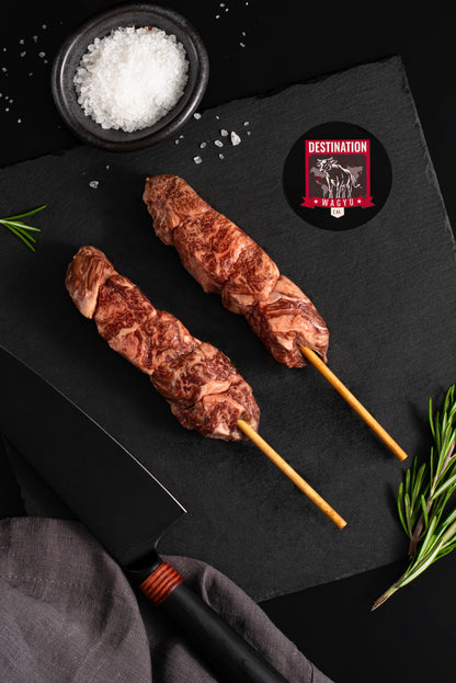 two Japanese A5 wagyu filet mignon skewers on a black board with salt and knife