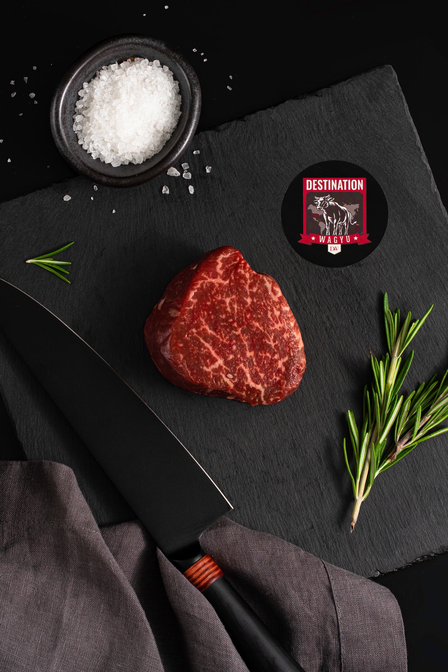 An australian wagyu 8oz filet mignon on a black board with knife and salt