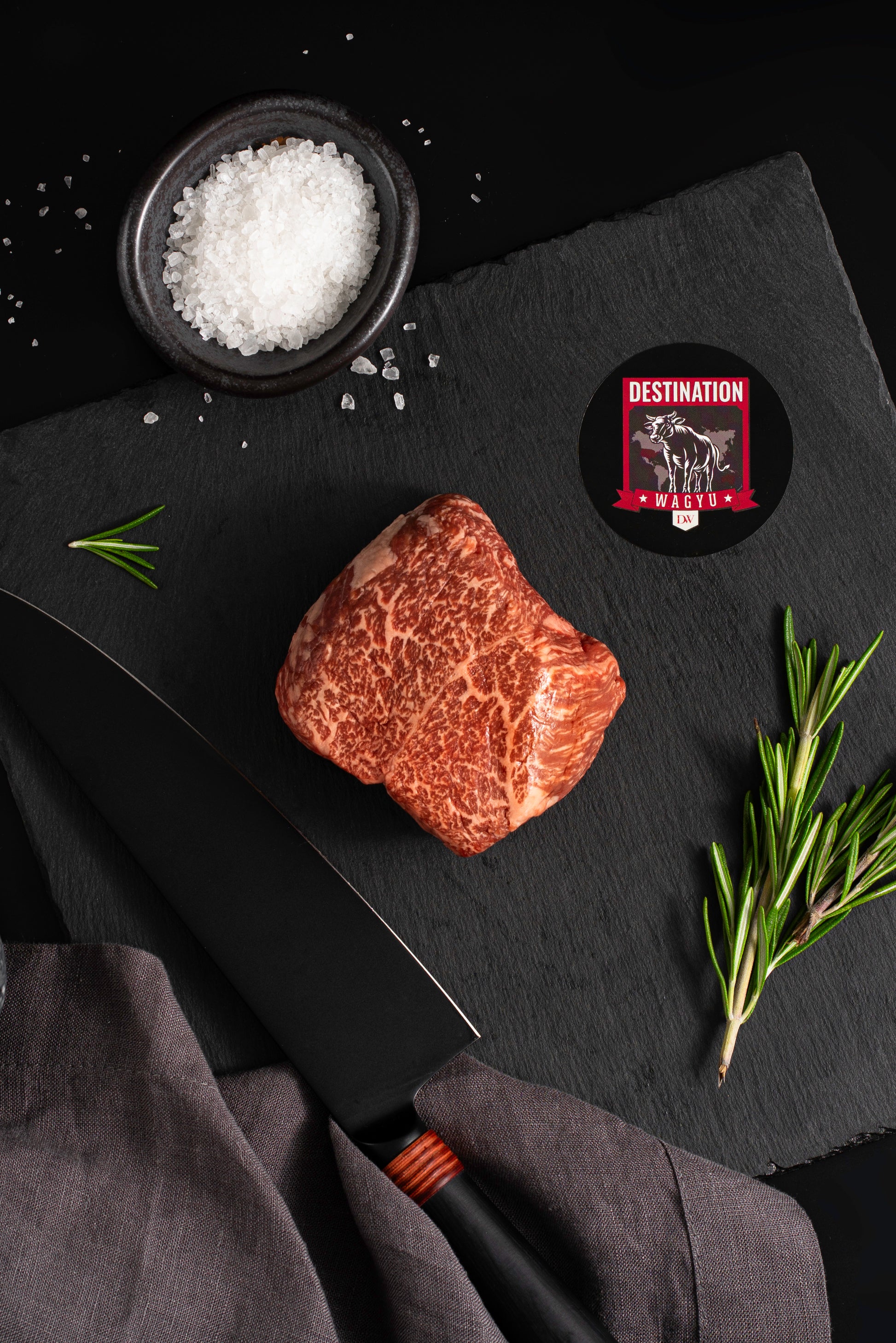 A Japanese a5 top sirloin wagyu steak on a black slate board with knife and salt