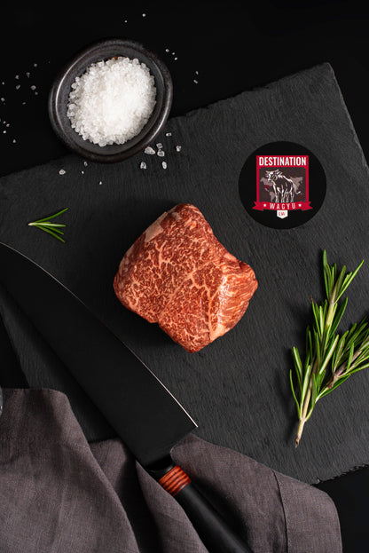 A Japanese a5 top sirloin wagyu steak on a black slate board with knife and salt