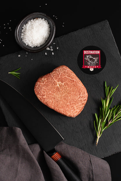 an 8oz Kobe Wine Japanese A5 wagyu filet mignon steak on a black board with salt and knife