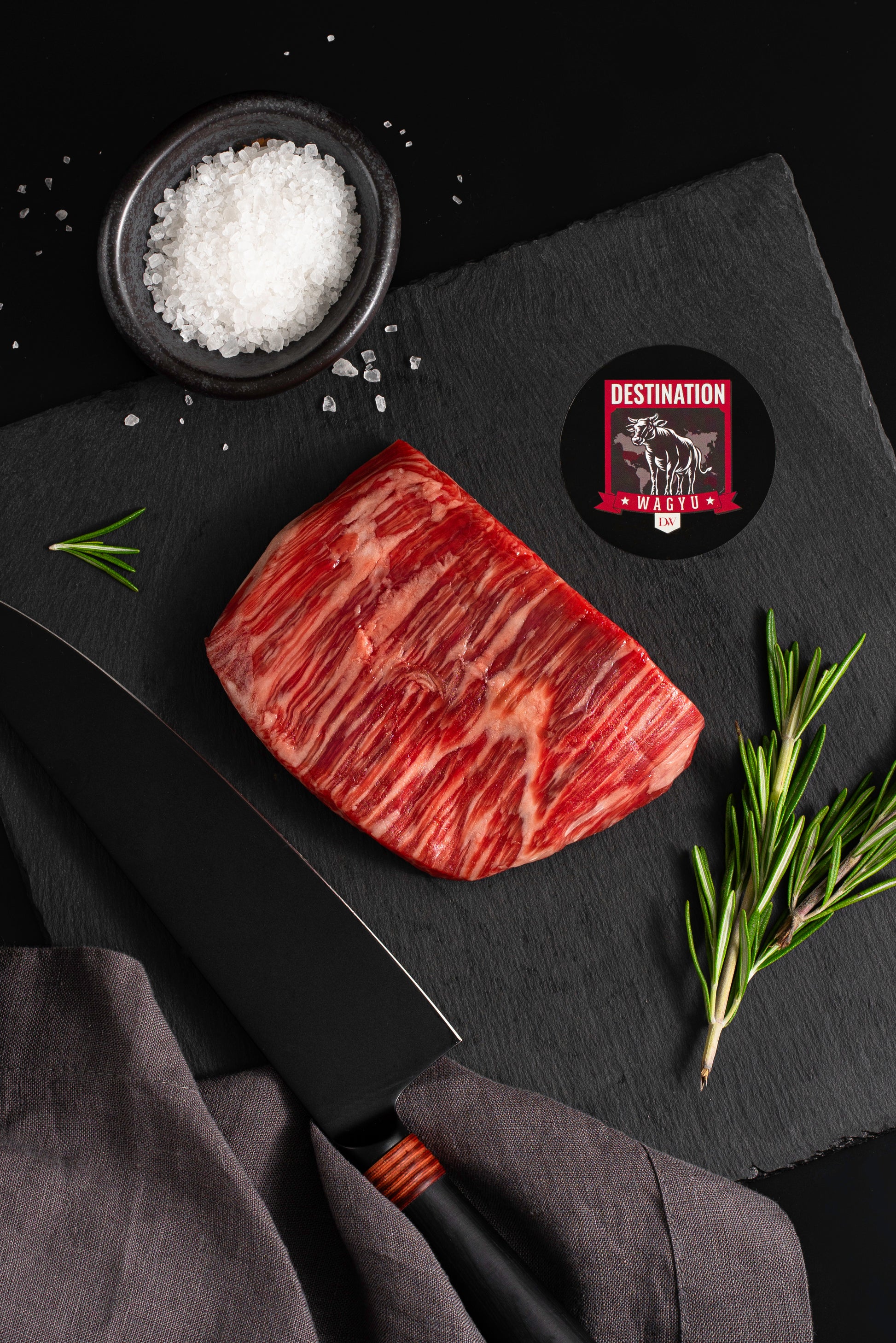 an Australian wagyu 8oz flank steak on a black board with salt and knife