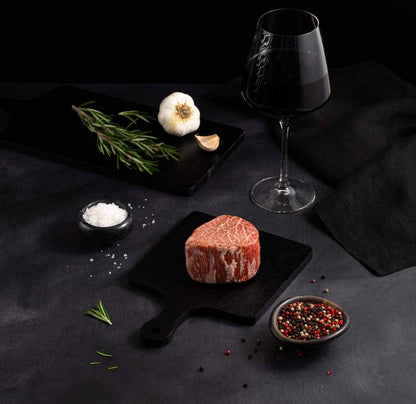 A Japanese A5 Wagyu Miyazaki Filet Steak with salt and chef's knife on a black slate, isolated on black background.